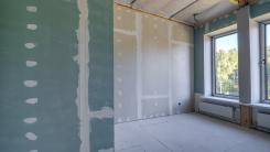 An empty room with bare, unpainted walls showing drywall and drywall seams