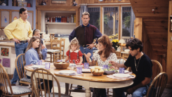 A screenshot from Full House featuring the full cast sitting around the dining table in the Tanner home