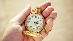 A gold pocket watch resting in a person's open palm