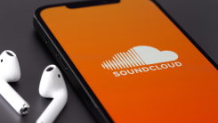 soundcloud app open on smartphone with earbuds lying nearby