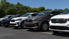 row of kia vehicles lined up in a row at a car lot