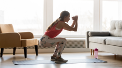A woman performing a squat exercise in her living room