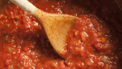 wooden spoon in a pot of traditional italian tomato sauce