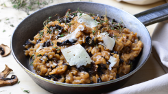 A bowl of hearty looking mushroom risotto with melting sheets of cheese on top
