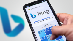 A person holding a phone displaying the Bing homepage