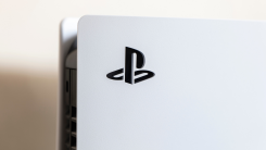 A close-up photograph of the top of a PlayStation 5, showing the PlayStation logo