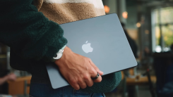 man carrying a macbook in his hand
