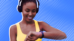 A woman wearing headphones and running gear looking at his smartwatch on her wrist