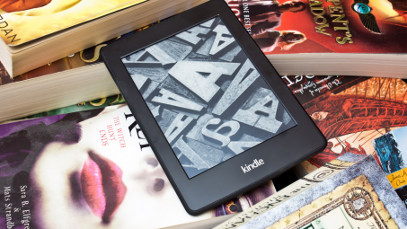 A Kindle on top of many books. 
