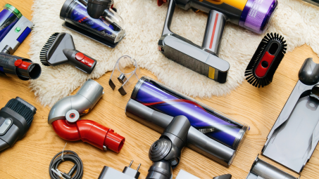 A collection of Dyson vacuum accessories neatly laid out on a wooden floor with a fluffy white rug