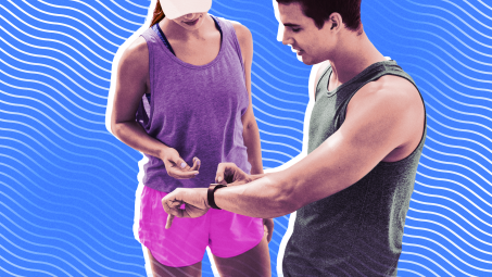 A man and woman in running gear in discussion, looking at the man's fitness tracker