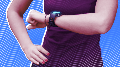 A woman in workout gear checking her fitness smartwatch