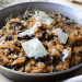 A bowl of hearty looking mushroom risotto with melting sheets of cheese on top