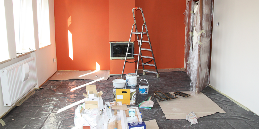 a room in the middle of renovation with paint cans on the floor and a ladder nearby