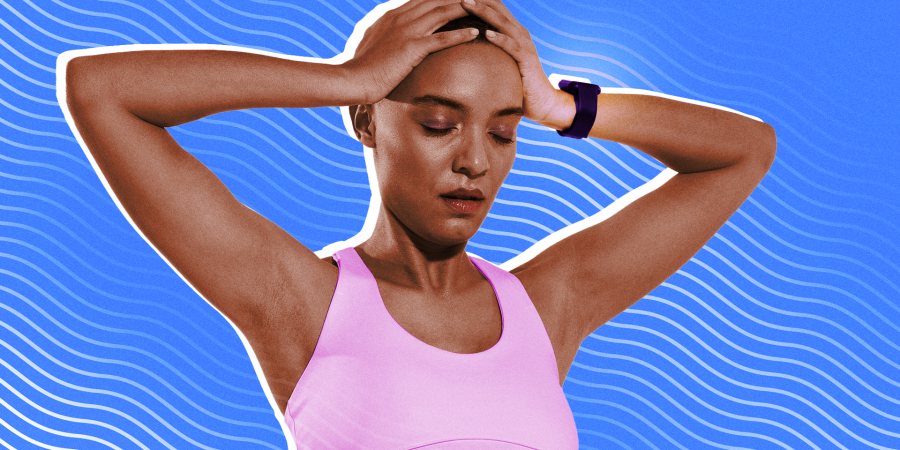 A woman in workout clothes and wearing a fitness tracker looking exasperated with her hands on her head