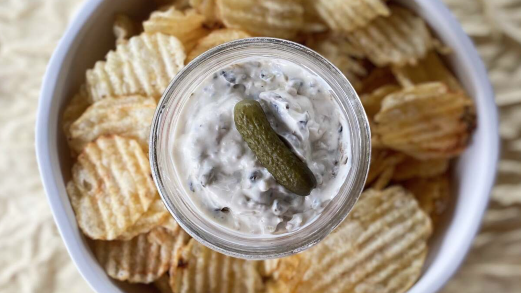 A small bowl of pickle dip on a bed of chips.